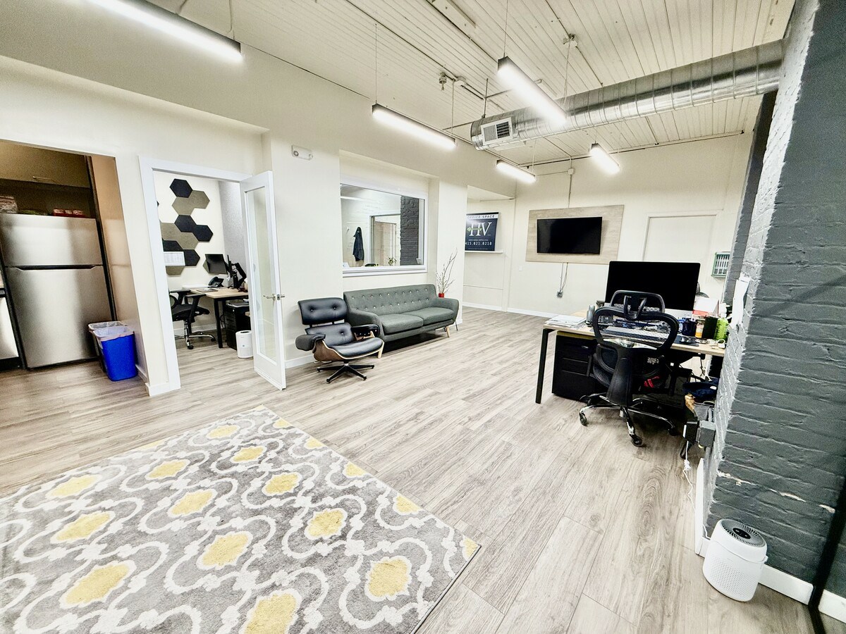 Open office with decorative rug and kitchenette view